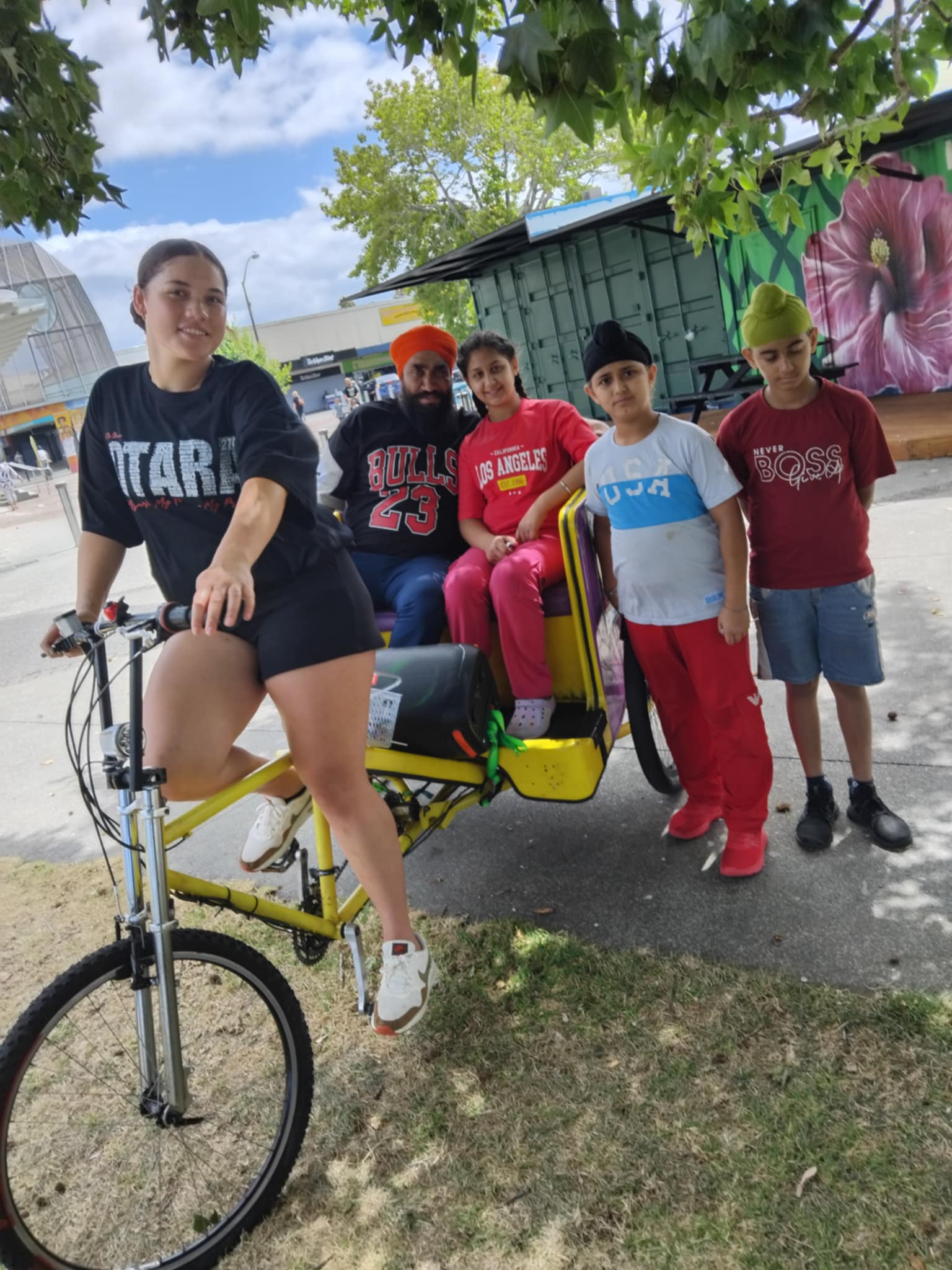Rangatahi cycling family around neighborhood.