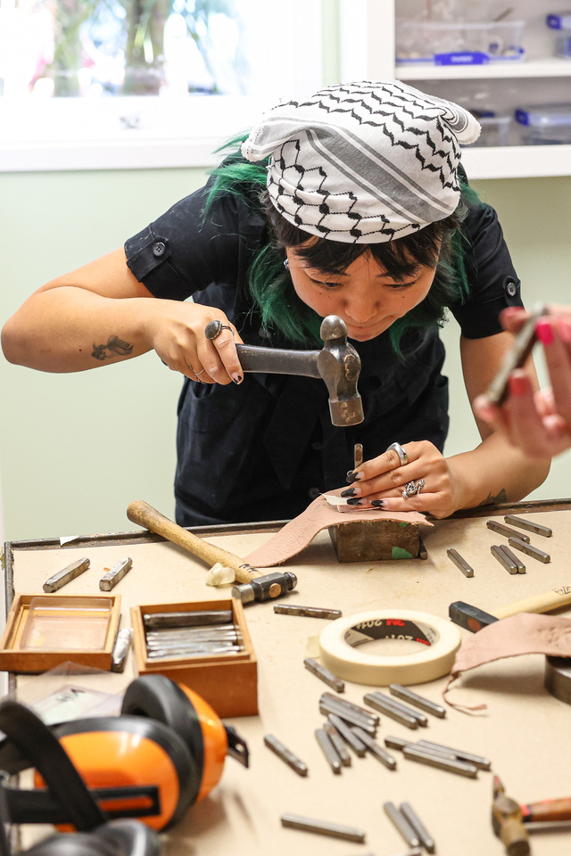 A woman working with tools to repair a item. 