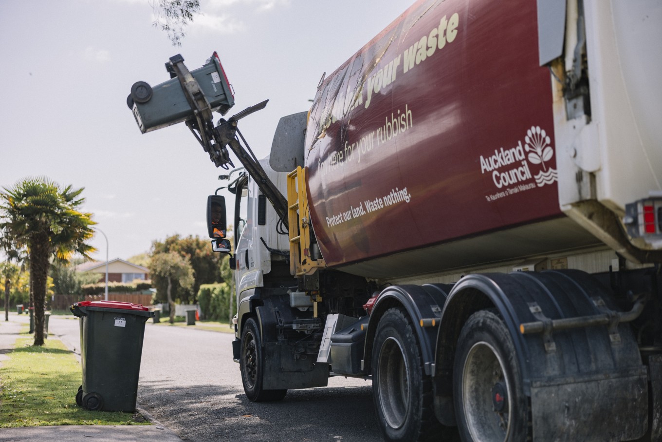 An Auckland Council rubbish truck collecting bins.  