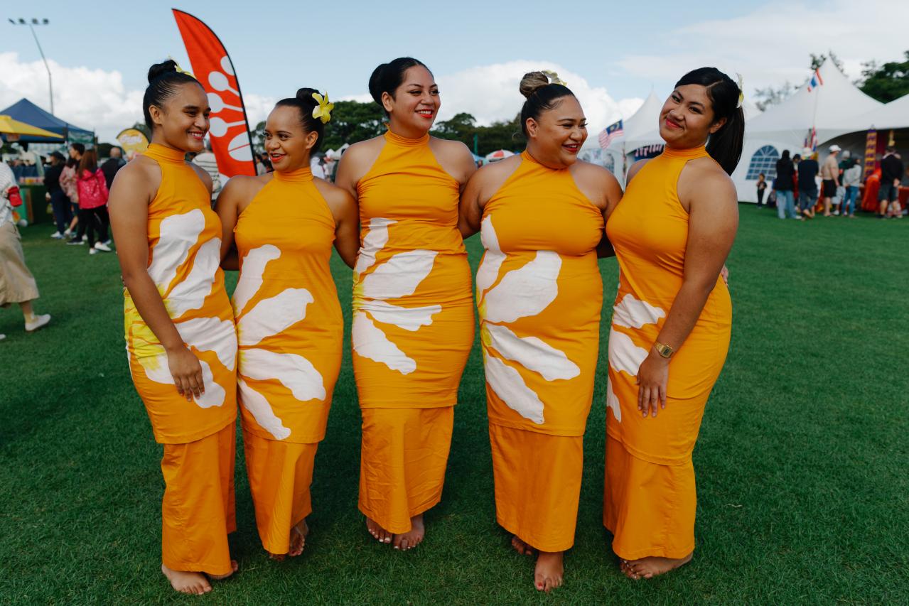 Polynesian dancers in traditional orange clothing.