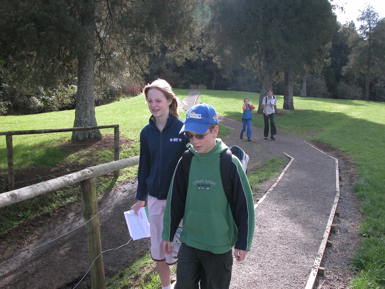 Family of 4 walking along a path between trees and grass