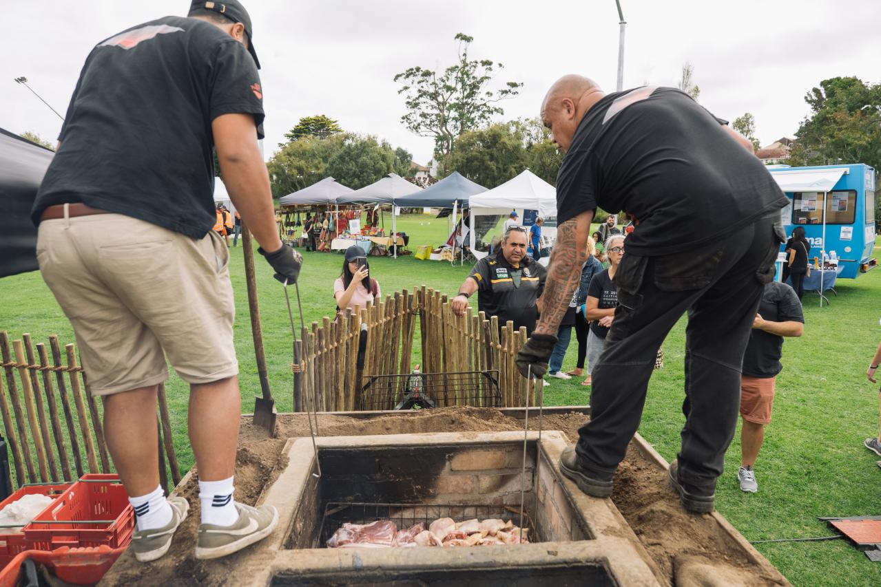 Some people digging a hangi pit.
