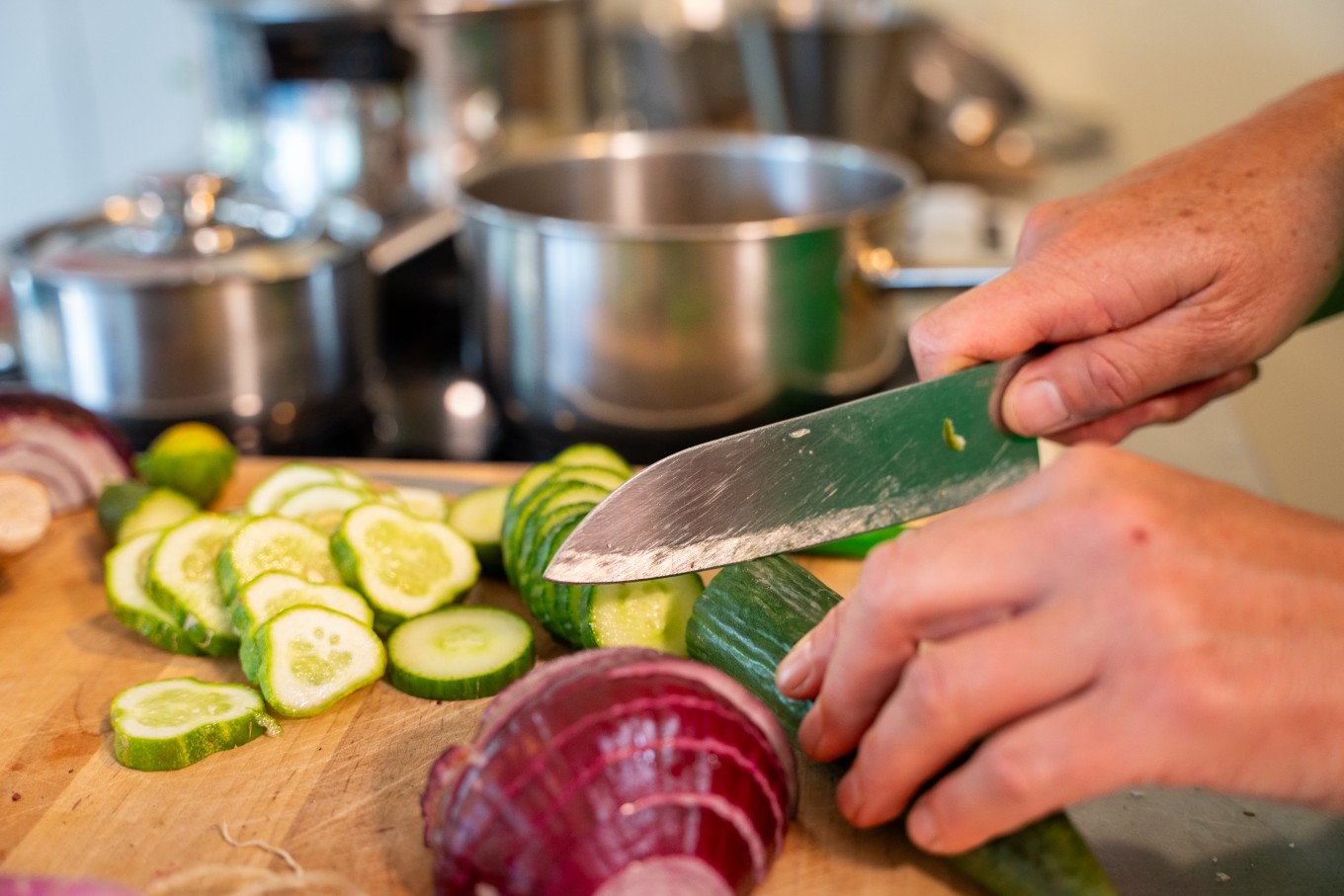 A person cutting a cucumber.