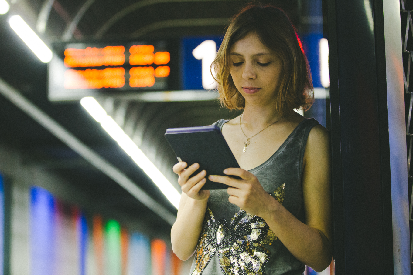 A person reading a book at the train station.