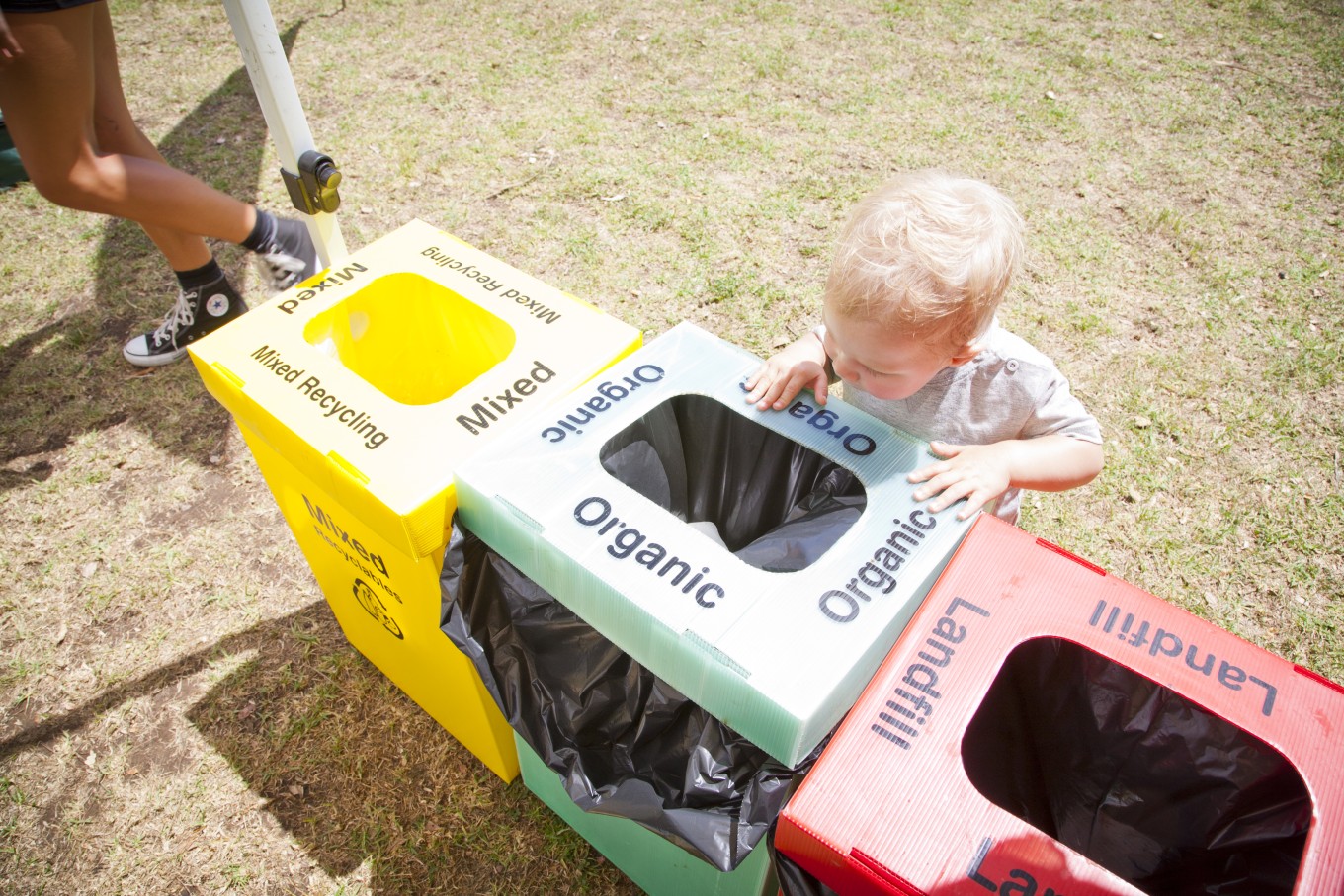 A child next to waste bins. 