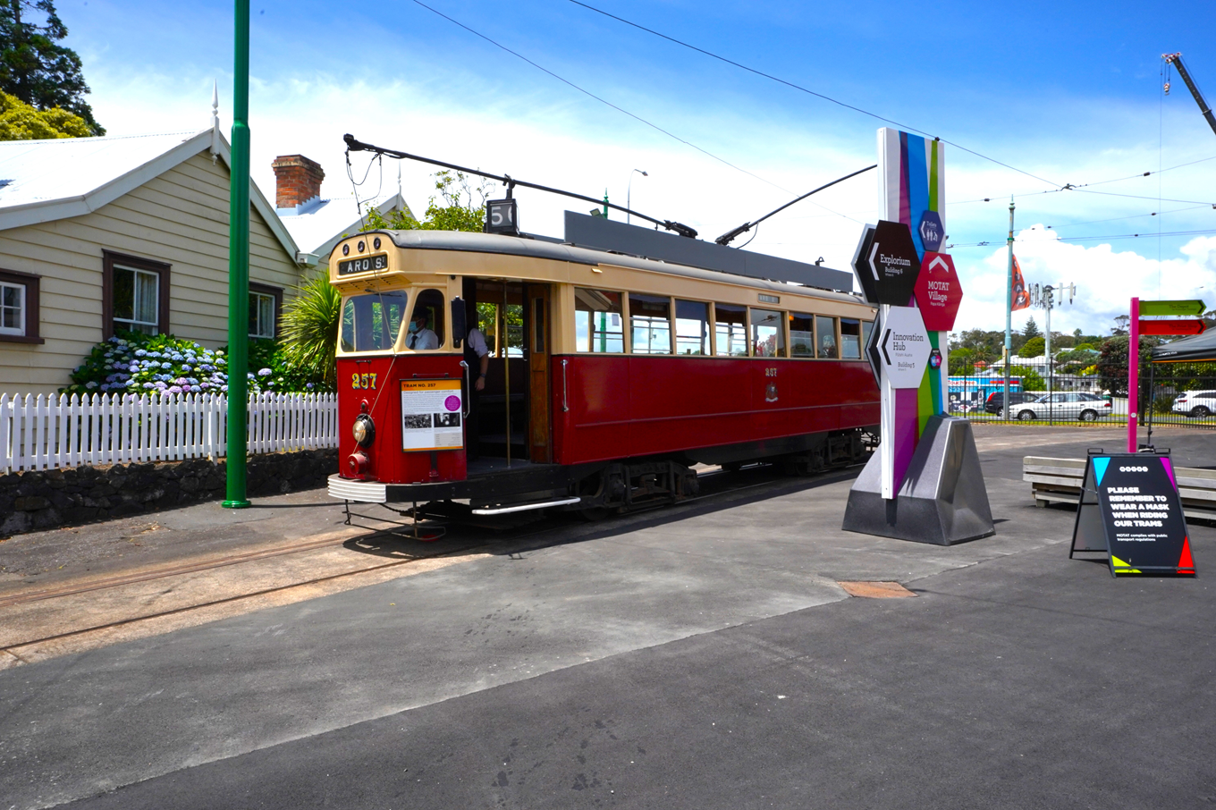 A red tram moving on tram tracks. 