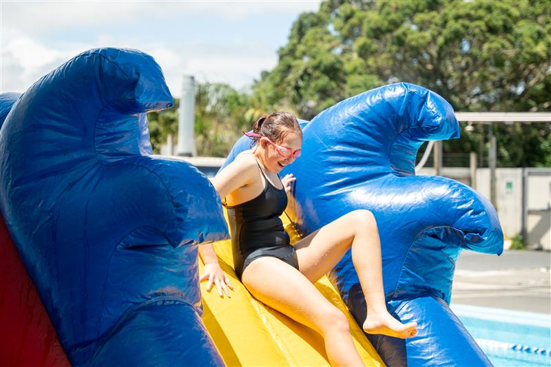 A girl sliding down a inflatable water slide. 