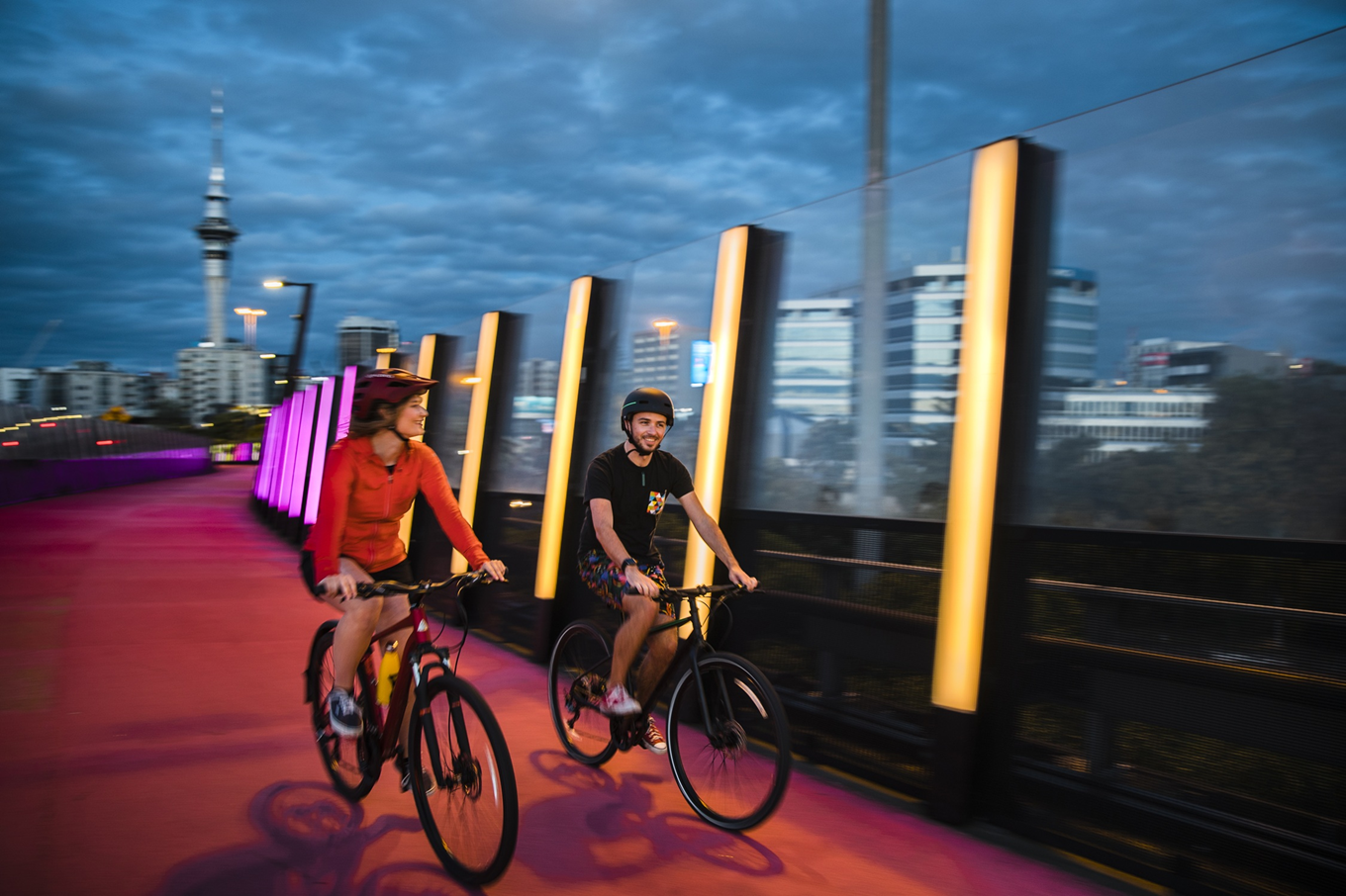 Two people riding bikes near a light path. 
