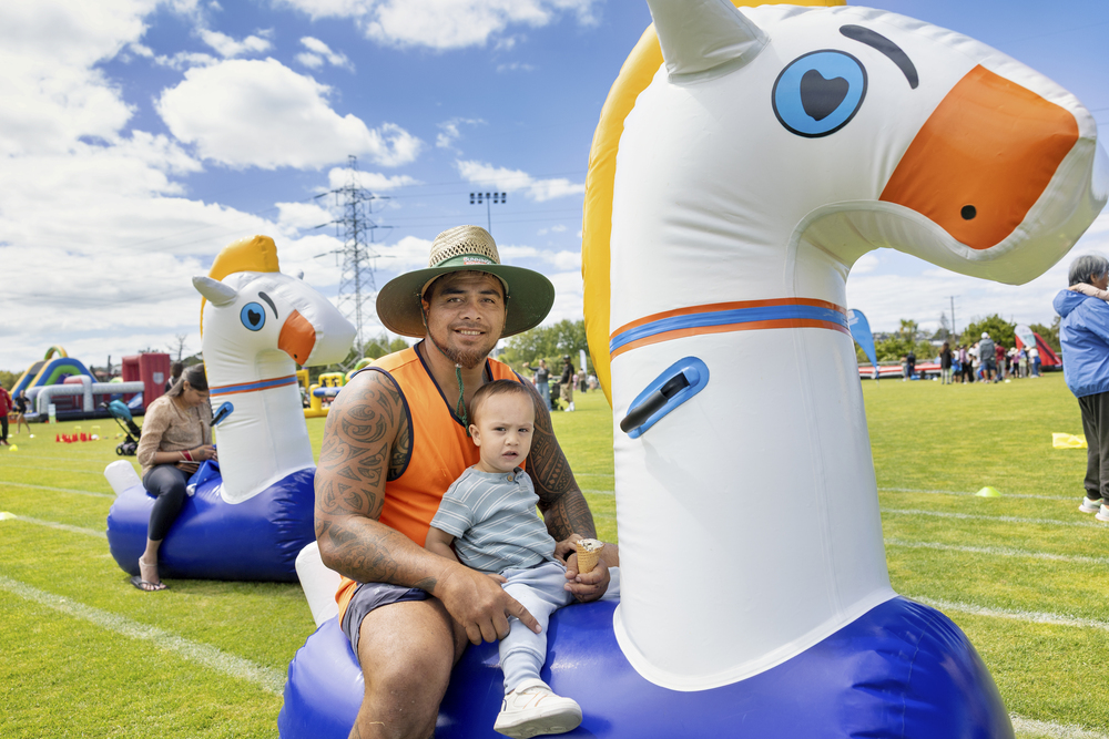 A father with his child on a inflatable animal.