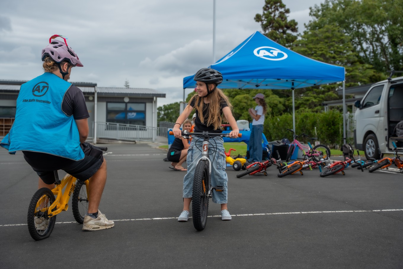 A person teaching a girl to ride a bike. 