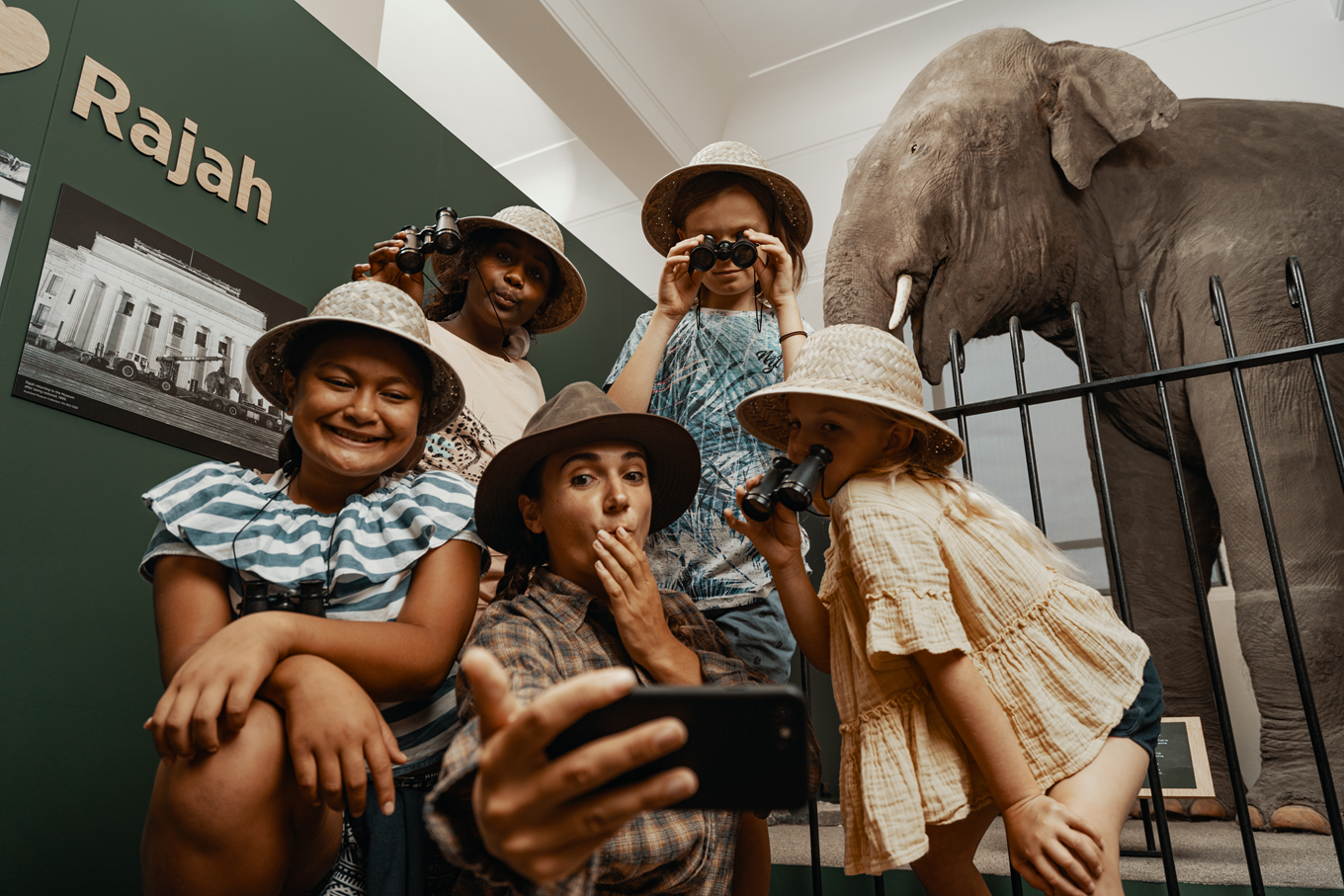 A lady with a group of girls at a exhibit in the musuem. 