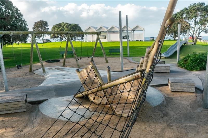The pirate-themed playground at Milford Reserve with the changing room and toilet block in the distance.
