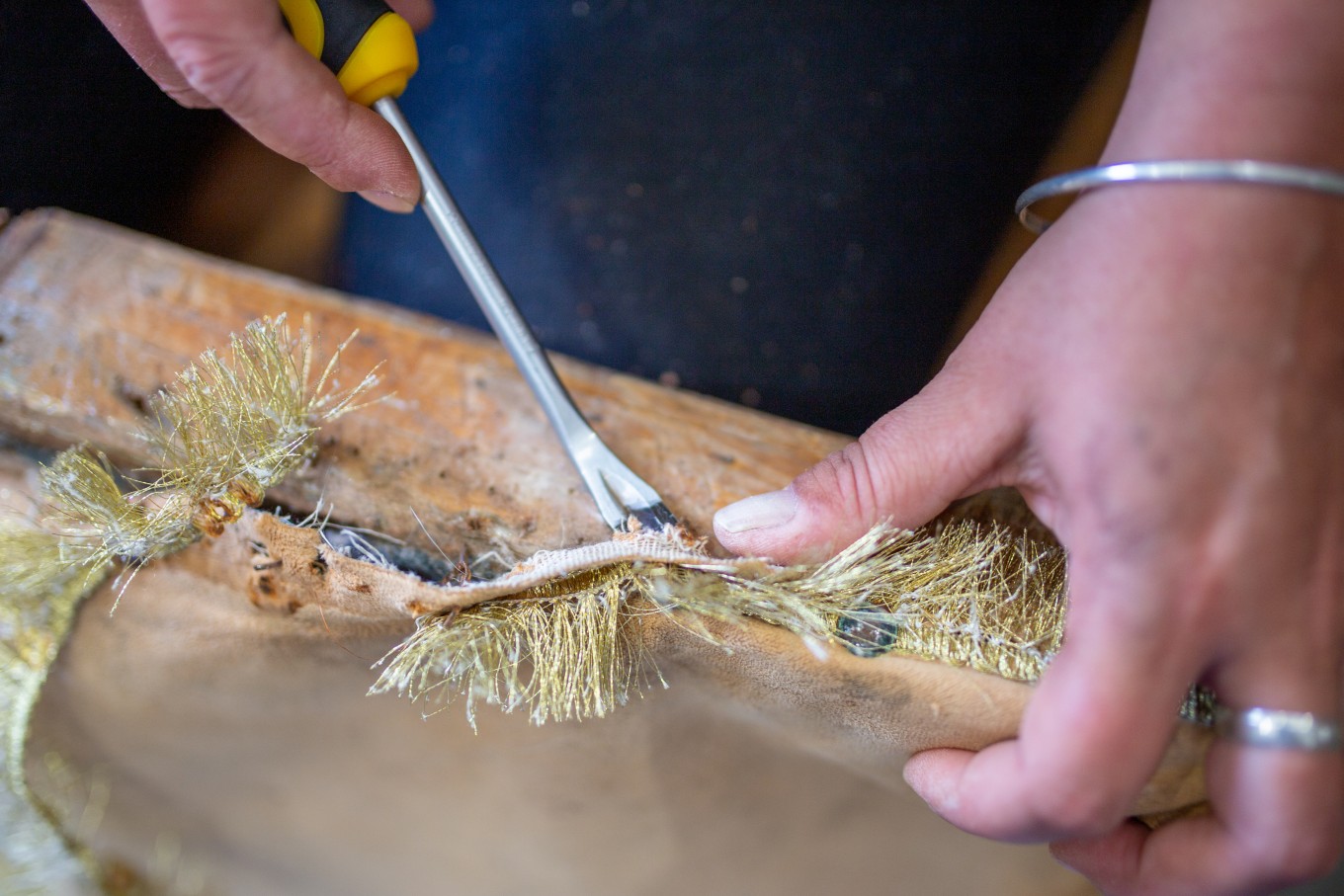 Close up of someone using a tool to fix a piece of furniture