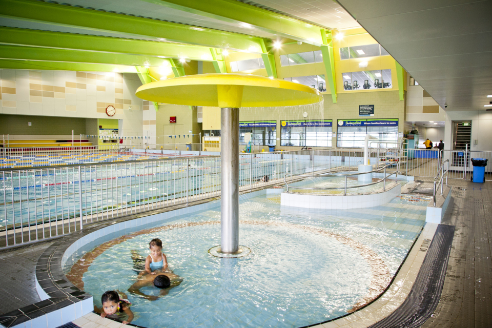 Kids swimming in the pool with a adult. 