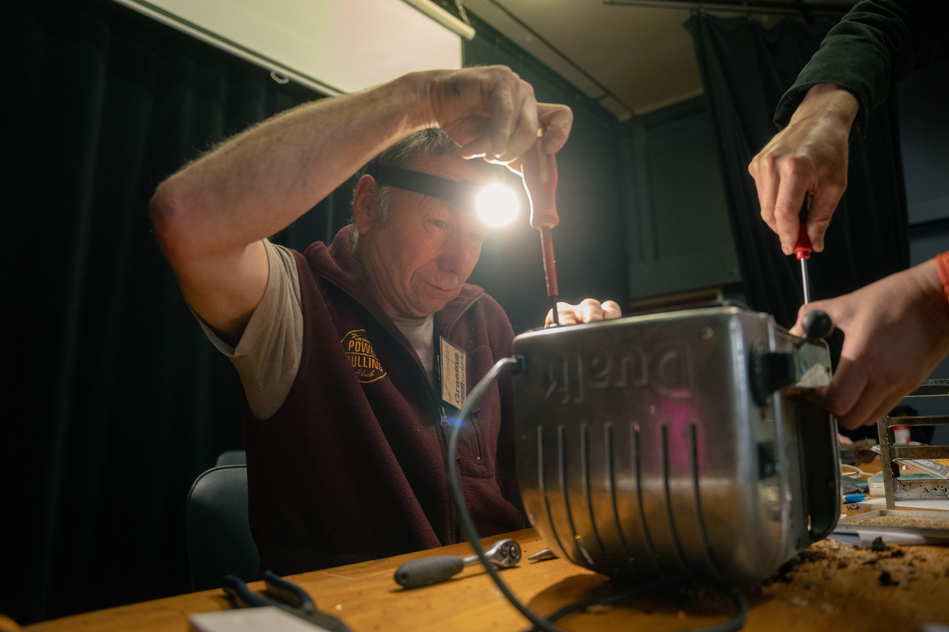 A man repairing a toaster. 