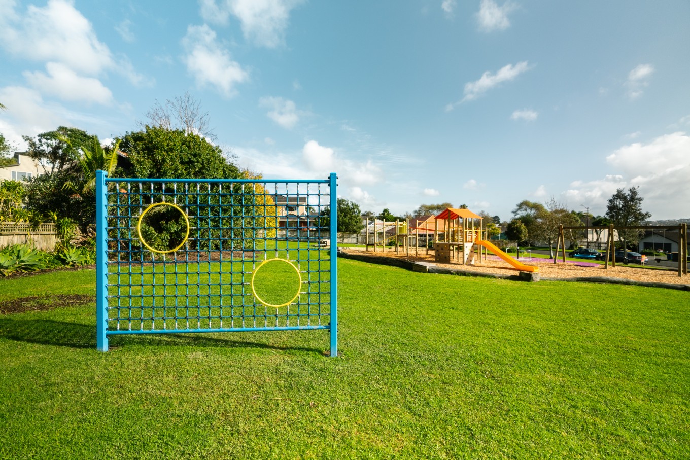 The soccer goal wall and climbing frame at Ponderosa Reserve playground is set on a grassy field, allowing kids space to run around while achieving their goals.