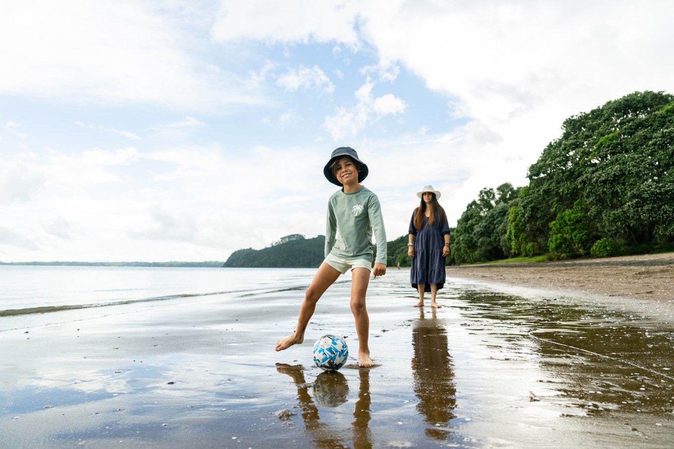 A child and adult standing on Cornwallis Beach with the beach stretching our behind