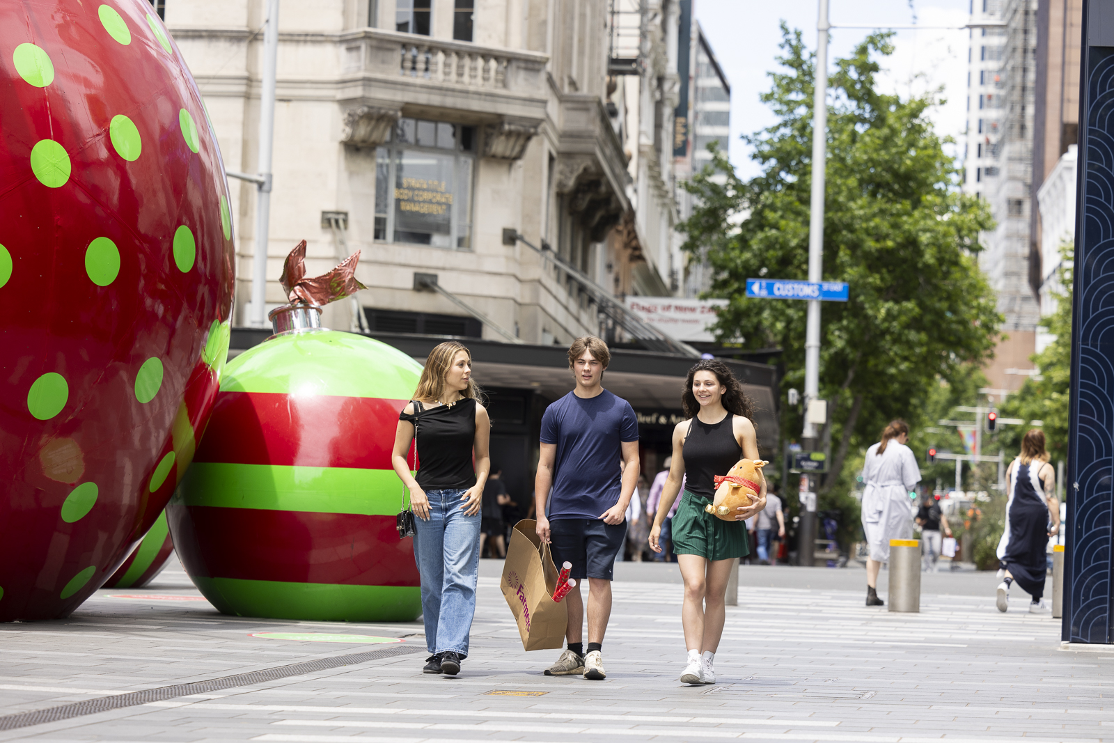 Young people walking by large christmas baubles. 