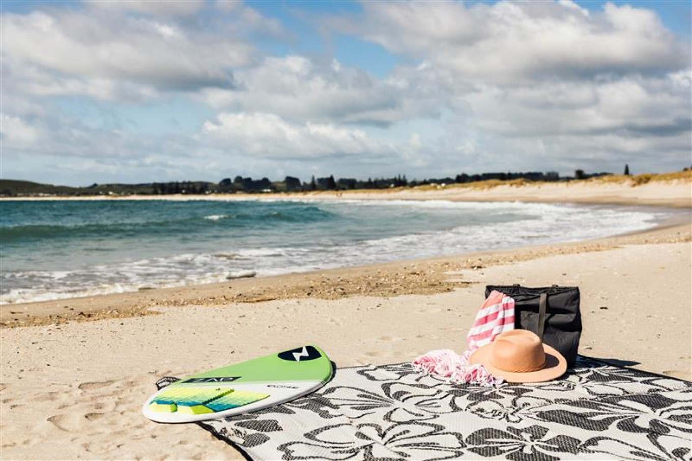 Beach gear set up including surfboard, hat and towel. 