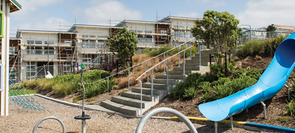 Buildings under construction, with a playground in the foreground. 