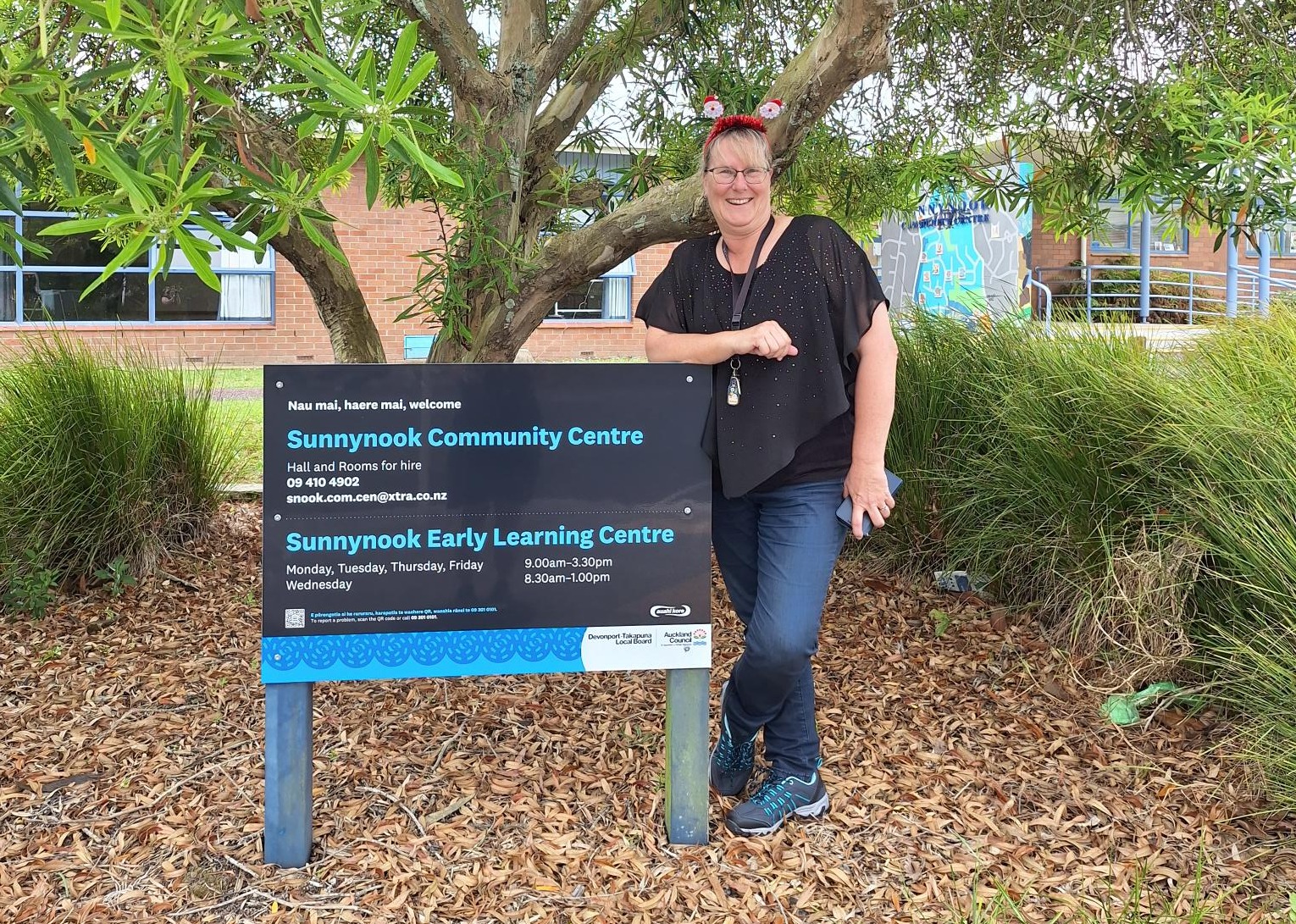 A lady standing by a sign. 