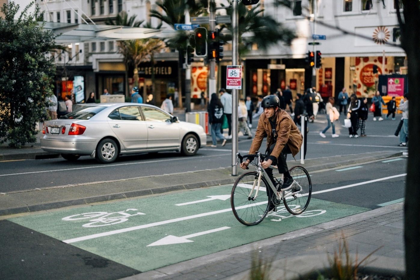 A guy cycling on a bike up Queen St. 