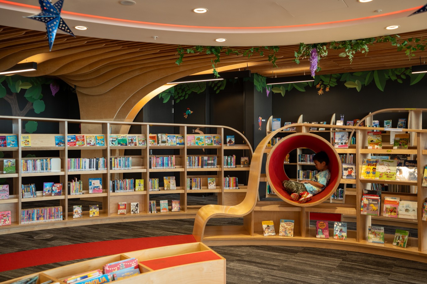 A child reading a book in the children's section of the library. 