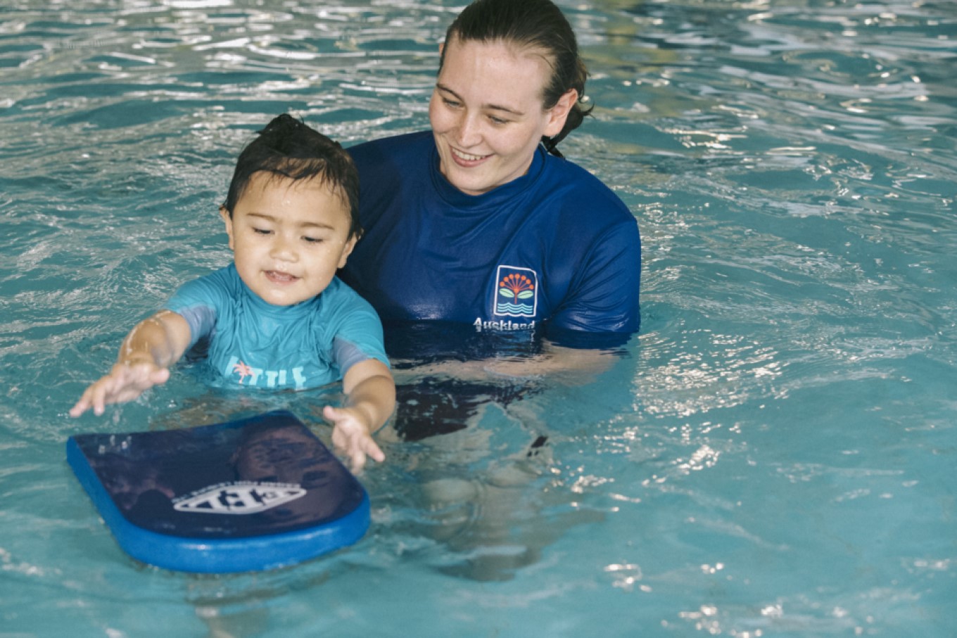Child learning to swim with instructor. 