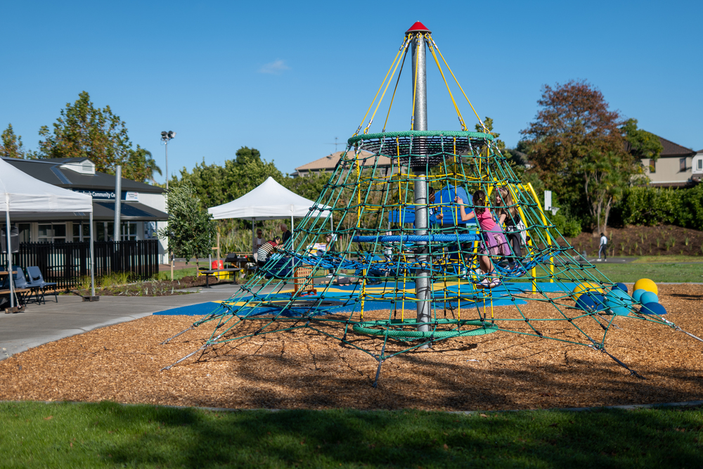 Two children climbing a colourful rope climbing frame in a playground.