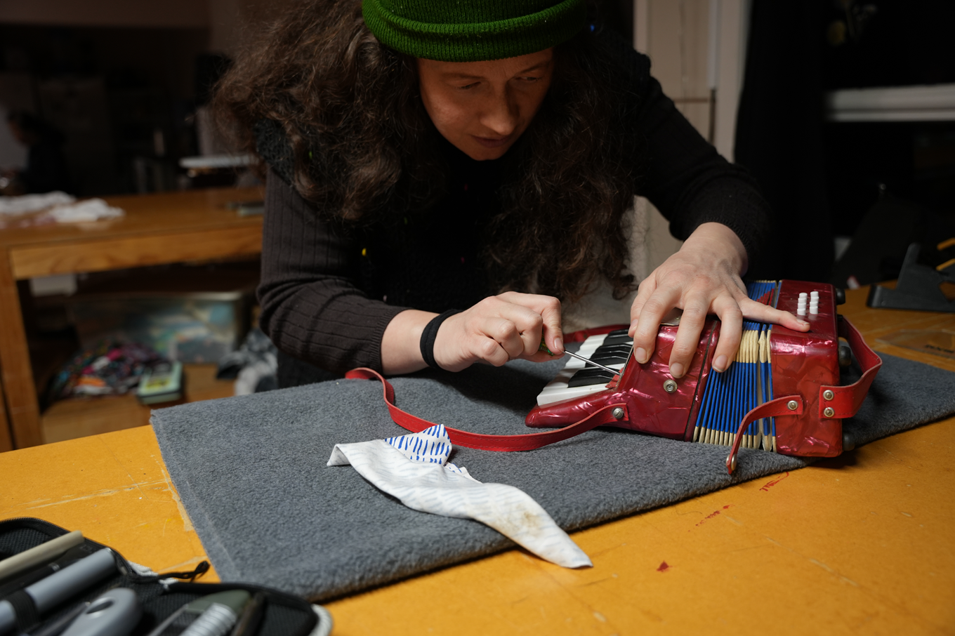 A woman repairing a accordion themed handbag. 