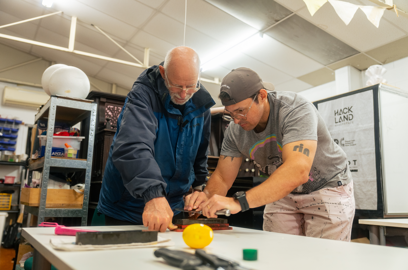 Two men sharping a collection of knives. 