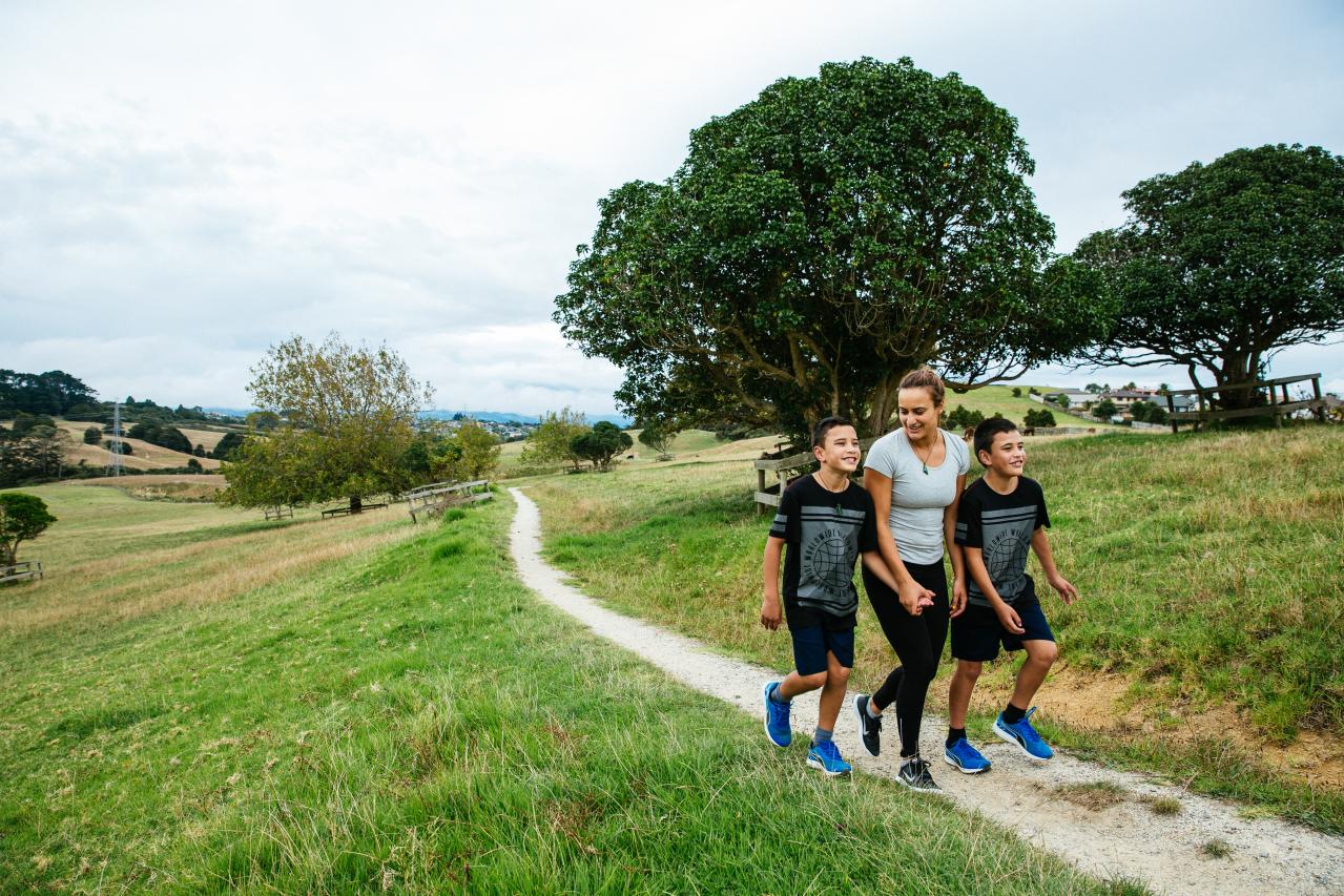 A lady walking with two boys in a local park. 