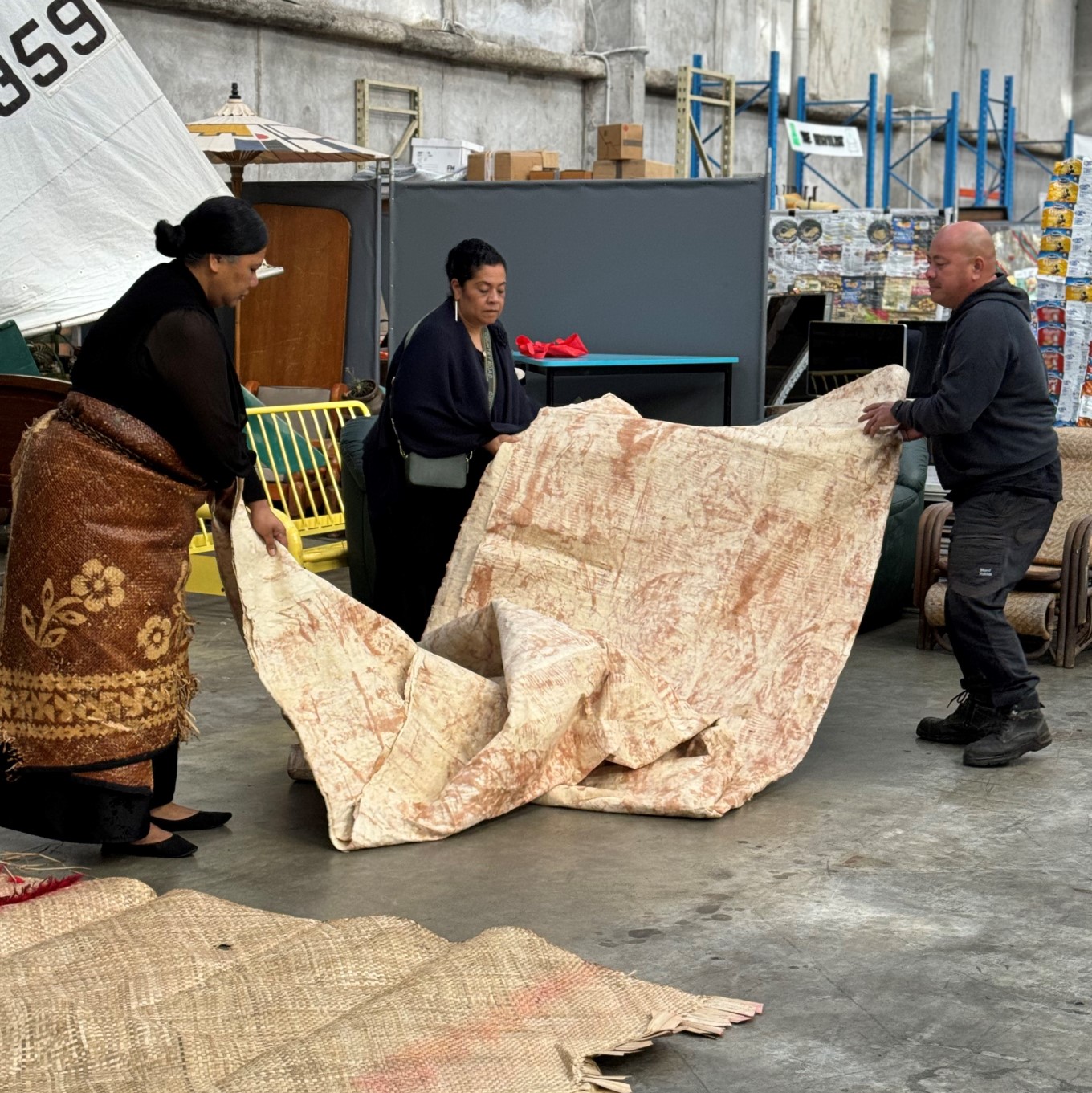 Pasifika staff at Community Recycling Centre unveiling thrown out Tapa mat. 