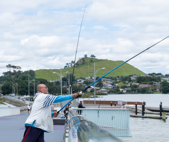 Guy fishing on bridge in Māngere