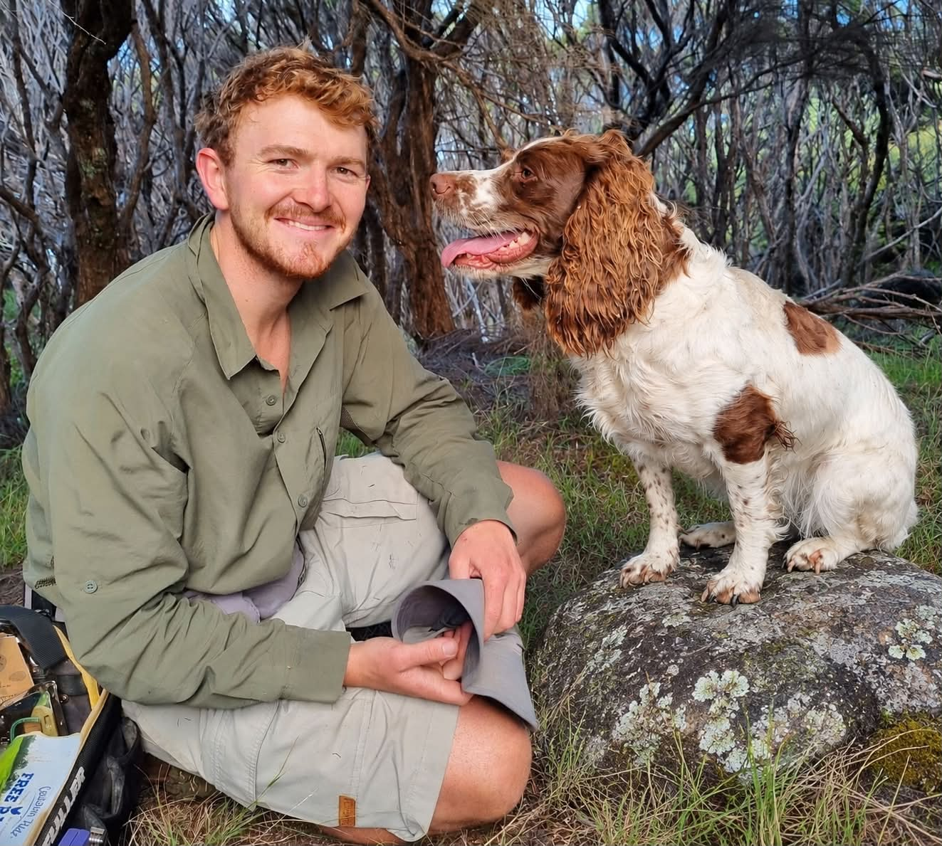 A man and his dog in a bush area.