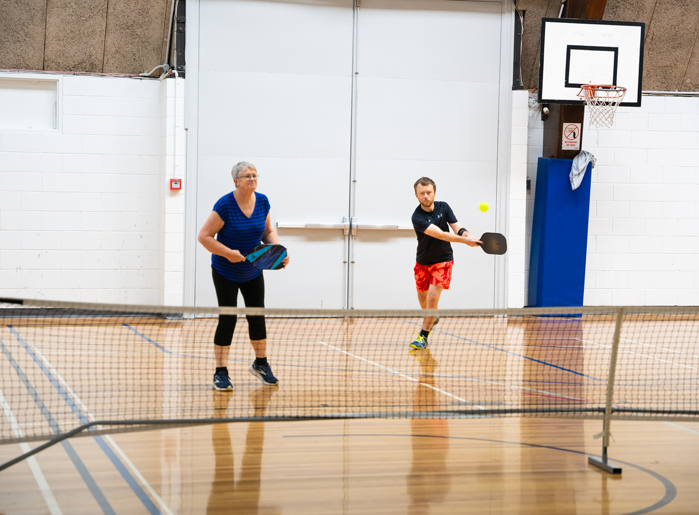 Two people playing pickleball on a court. 