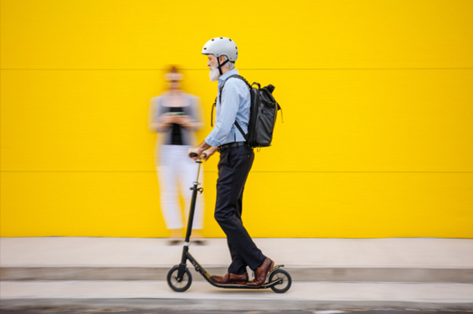 Person on a scooter riding past a yellow wall
