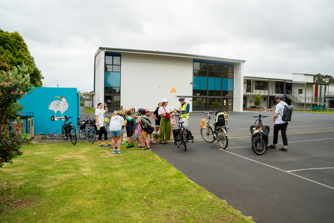 A lady showing kids how to ride a bike.
