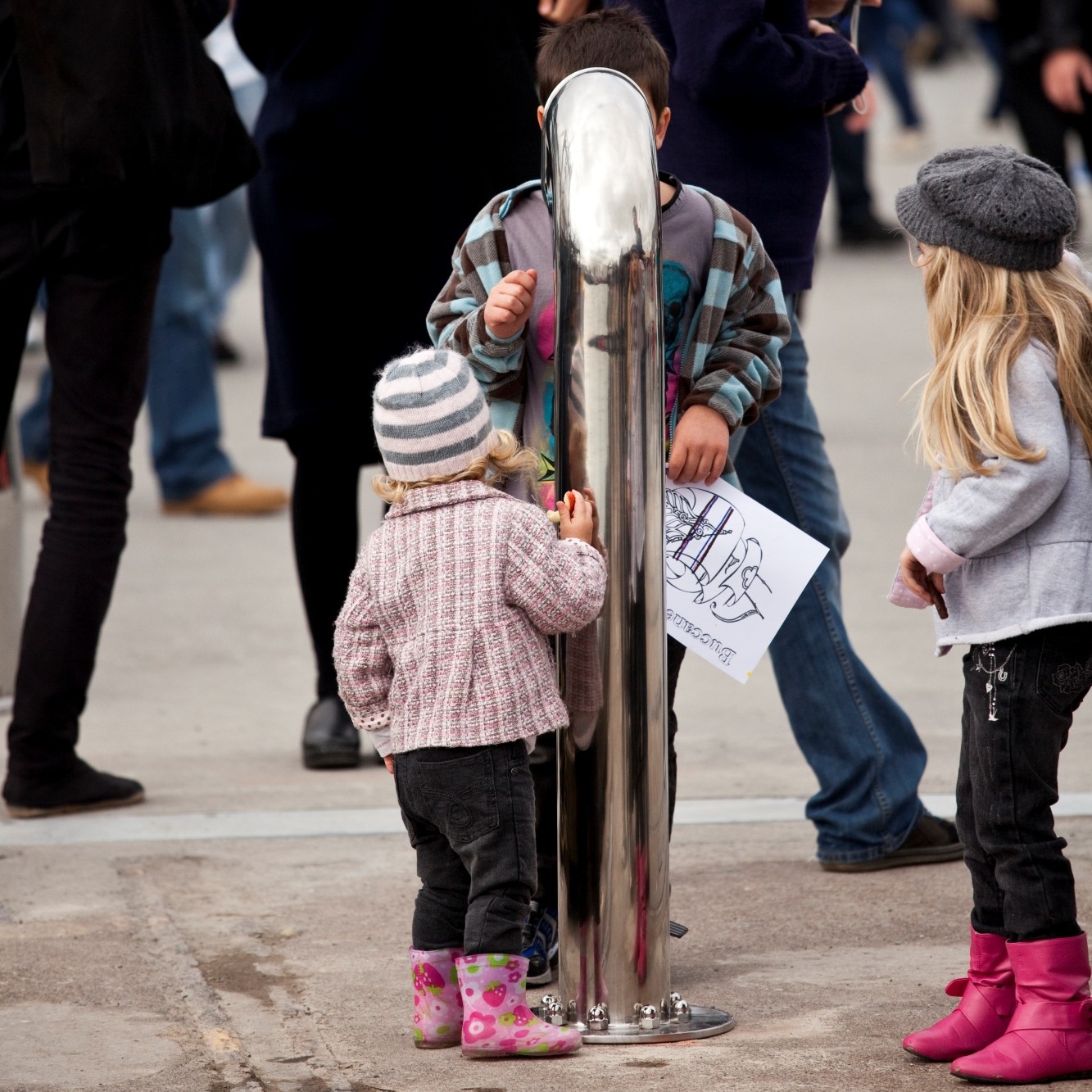 Some children shouting into a metal pipe.