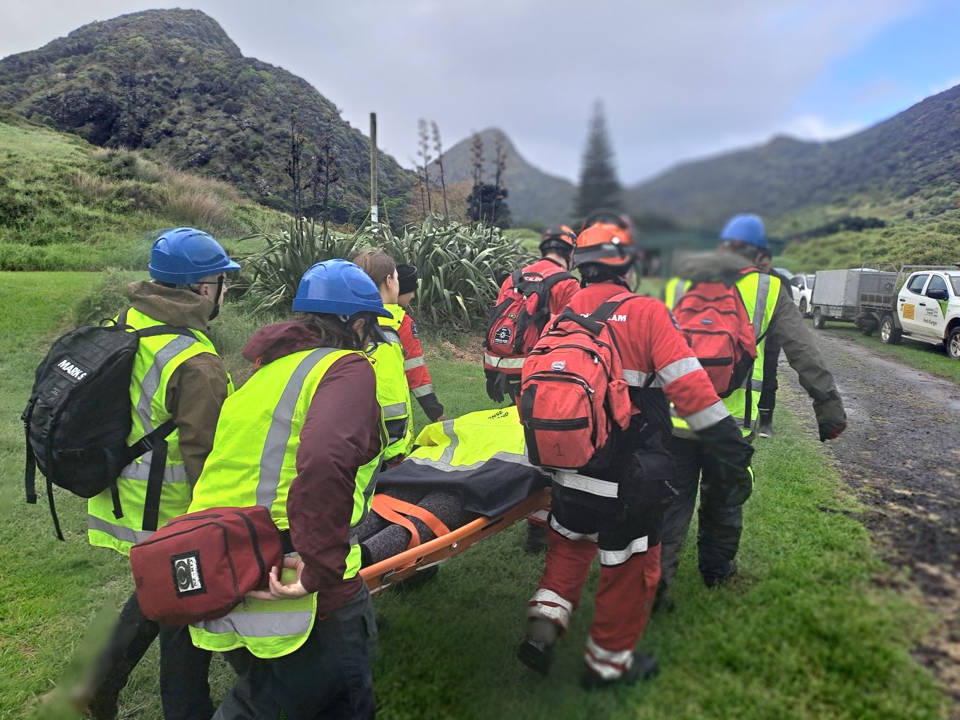Person being carried by workers on a stretcher. 