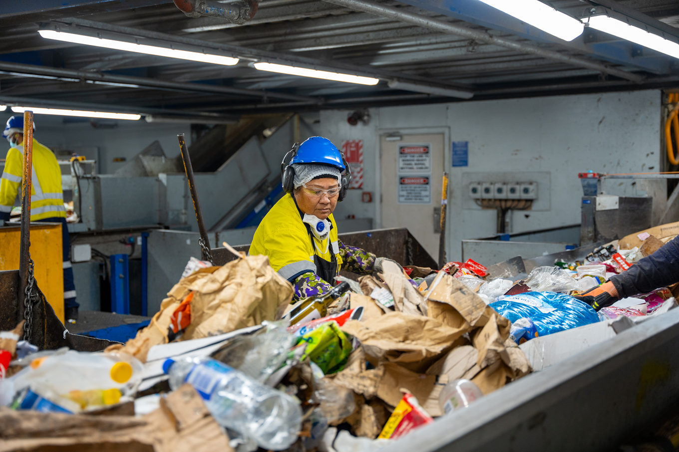 An Auckland Council worker sorting through rubbish and recycling waste at a recycle plant. 