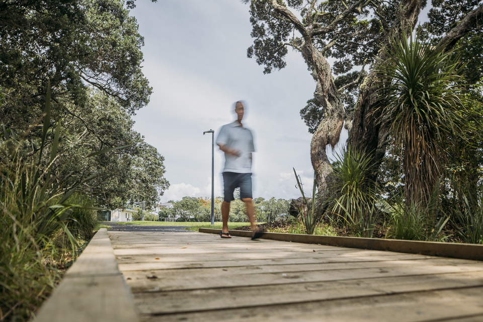 A guy walking down a boardwalk. 