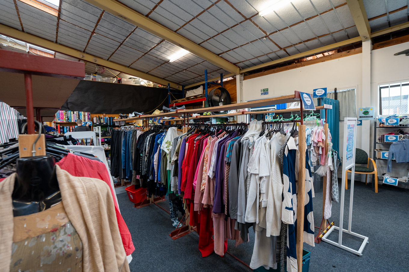 Clothing racks displaying clothes at a community recycling centre.