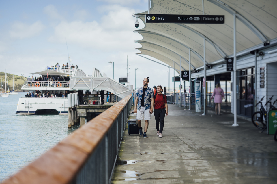Two people walking down a ferry terminal. 