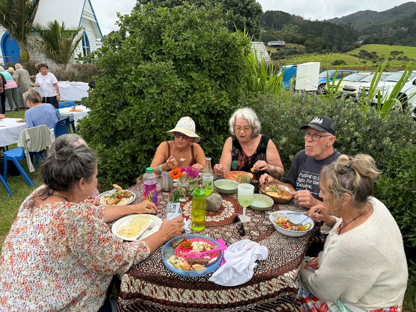 People sitting around an outdoor table eating food.