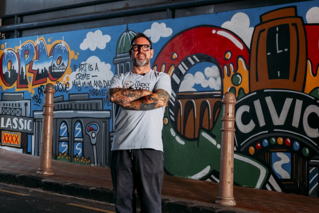 A man standing in fornt of a street mural. 