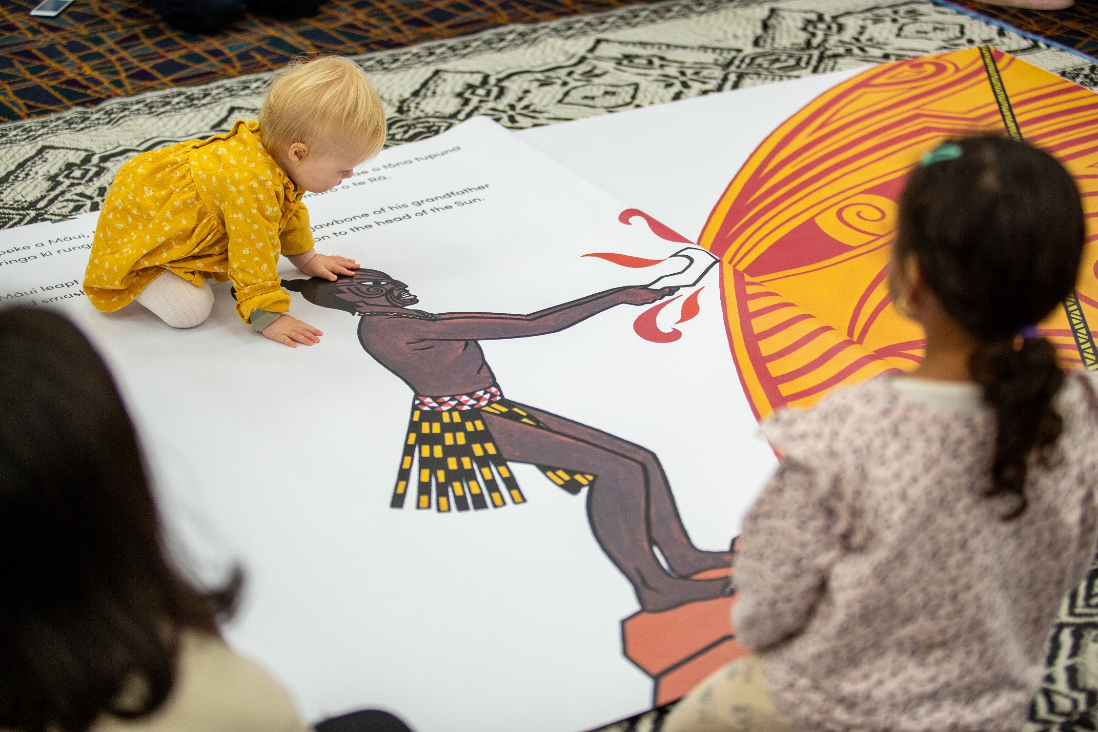 A child reading the giant book of Maui and the sun. 