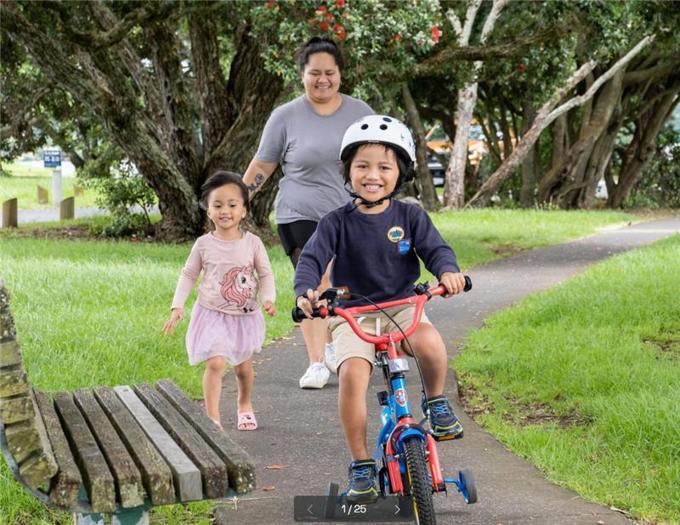 Young boy riding bike with his family in the park