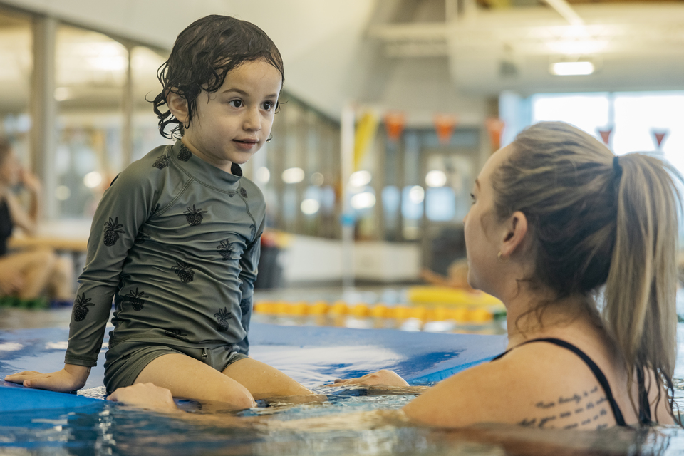 A child sitting on the edge of a swimming pool. 